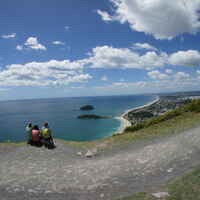 A photo of three people on top of a mountain looking at the sea